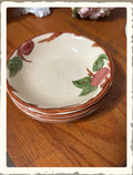 Stack of vintage Franciscan Apple pattern small bowls with hand-painted apple and leaf design on wood surface