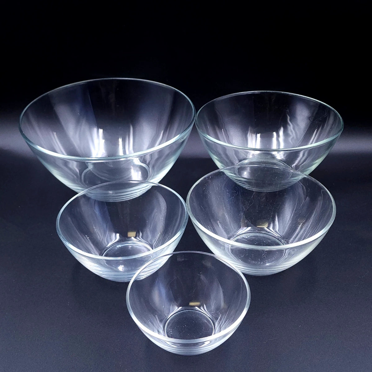 Set of 5 clear glass cat bowls in graduated sizes arranged on dark background