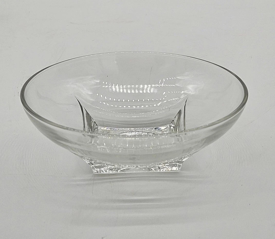 Modern clear glass bowl with thick square base and wide flared rim on white background